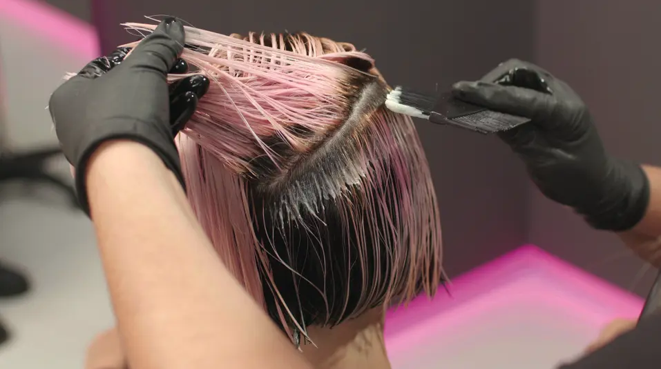 Hairdresser’s hands applying the hair color of the season